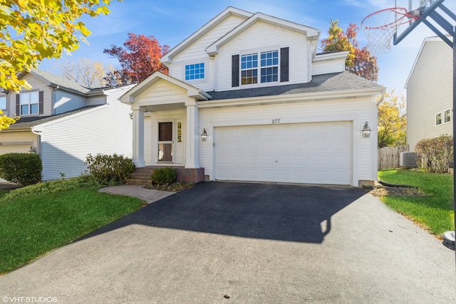 view of front of house with cooling unit, a garage, and a front lawn