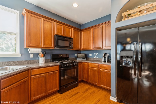 kitchen with black appliances, sink, and light wood-type flooring