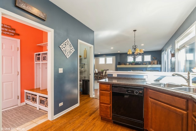 kitchen featuring black dishwasher, a chandelier, sink, light hardwood / wood-style floors, and decorative light fixtures