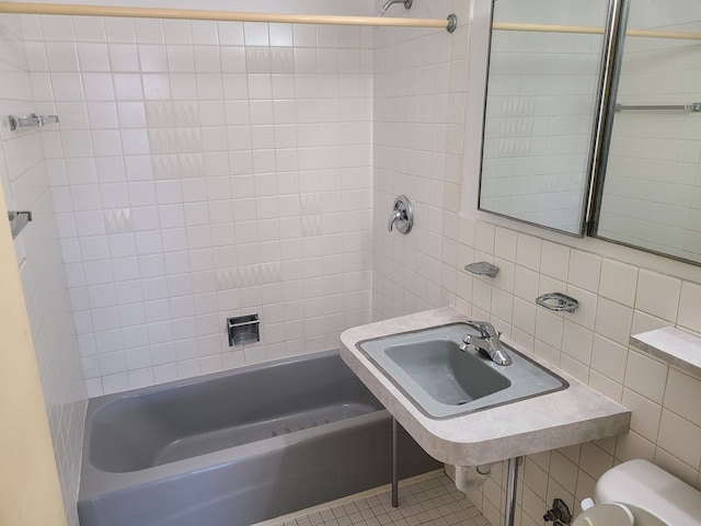 full bathroom with toilet, tiled shower / bath combo, tile patterned flooring, and tile walls