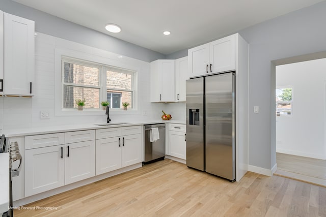 kitchen with white cabinetry, light hardwood / wood-style flooring, stainless steel appliances, and sink