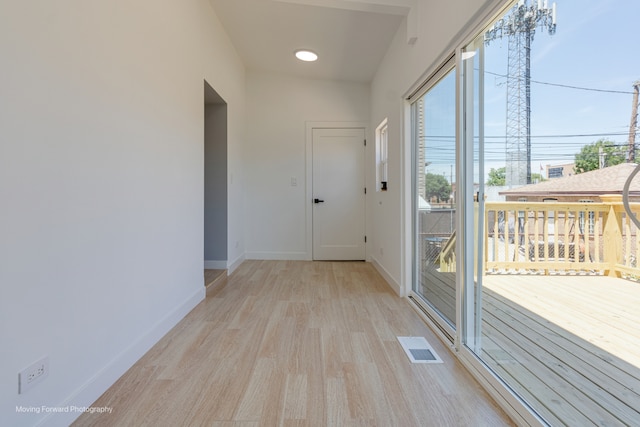 corridor featuring lofted ceiling and light hardwood / wood-style floors