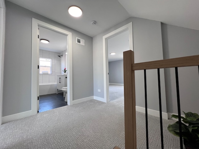 corridor with dark carpet and lofted ceiling