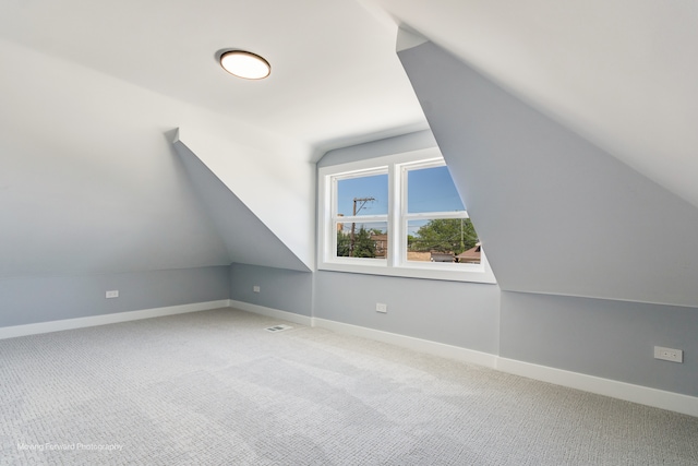 additional living space featuring lofted ceiling and carpet flooring