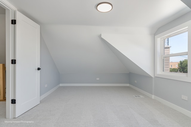 additional living space featuring lofted ceiling and light carpet