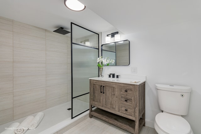 bathroom with toilet, vanity, and tiled shower