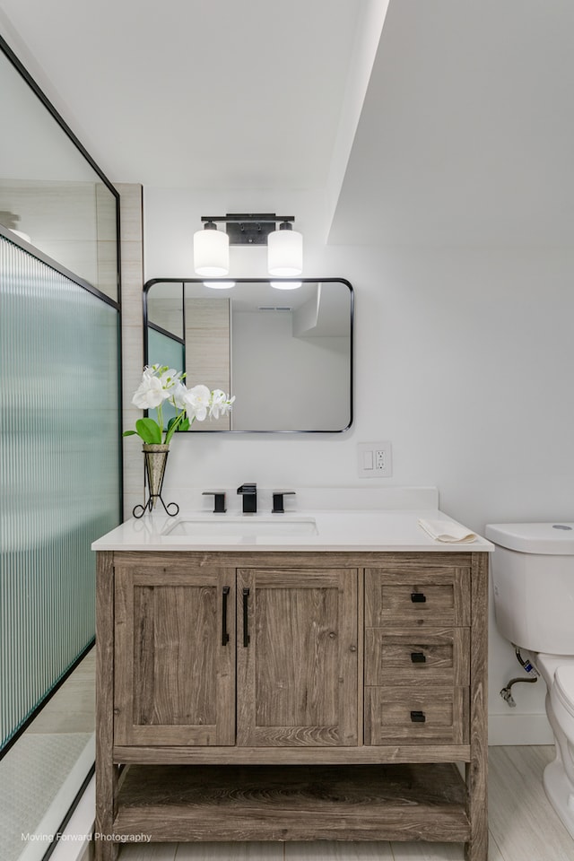 bathroom featuring vanity, toilet, hardwood / wood-style flooring, and an enclosed shower