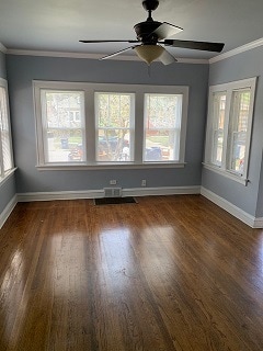 spare room featuring crown molding, dark wood-type flooring, and ceiling fan