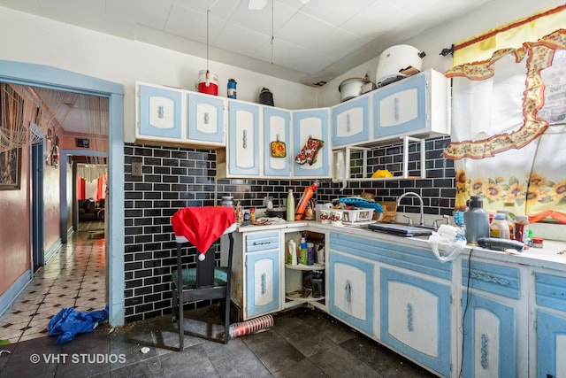 kitchen featuring blue cabinets, decorative backsplash, sink, and dark tile patterned flooring