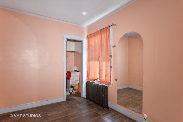 spare room with crown molding, radiator heating unit, and dark hardwood / wood-style floors