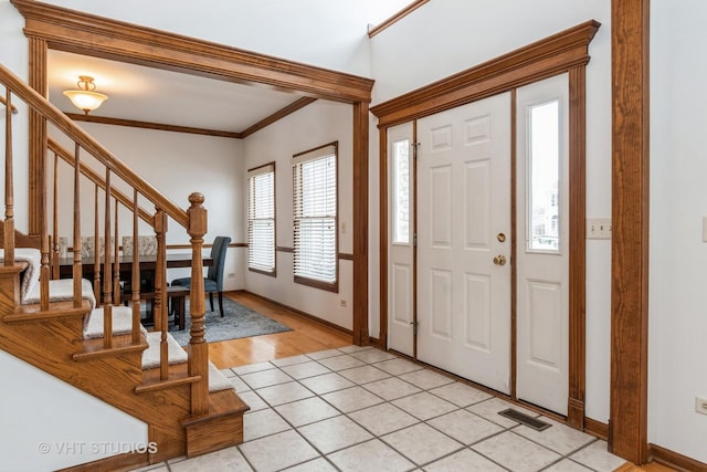 tiled foyer featuring ornamental molding