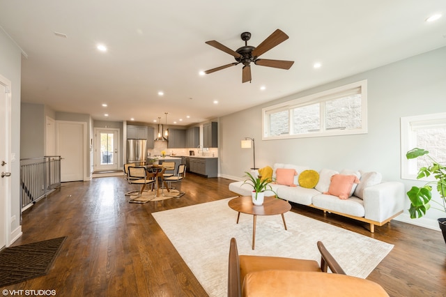 living room with dark wood-type flooring, a wealth of natural light, and ceiling fan