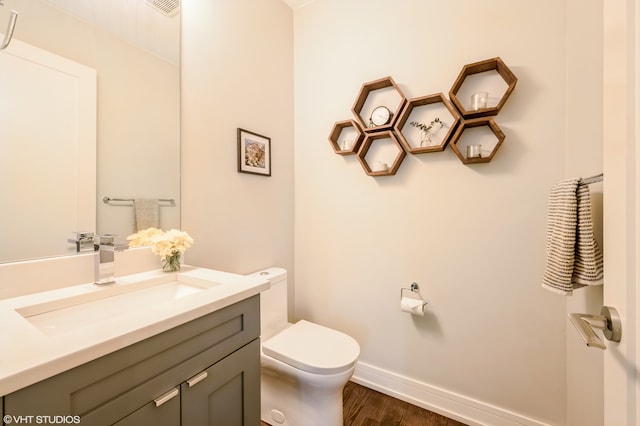 bathroom with toilet, vanity, and hardwood / wood-style floors