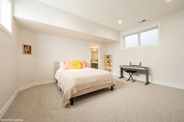 carpeted bedroom featuring ensuite bathroom and multiple windows