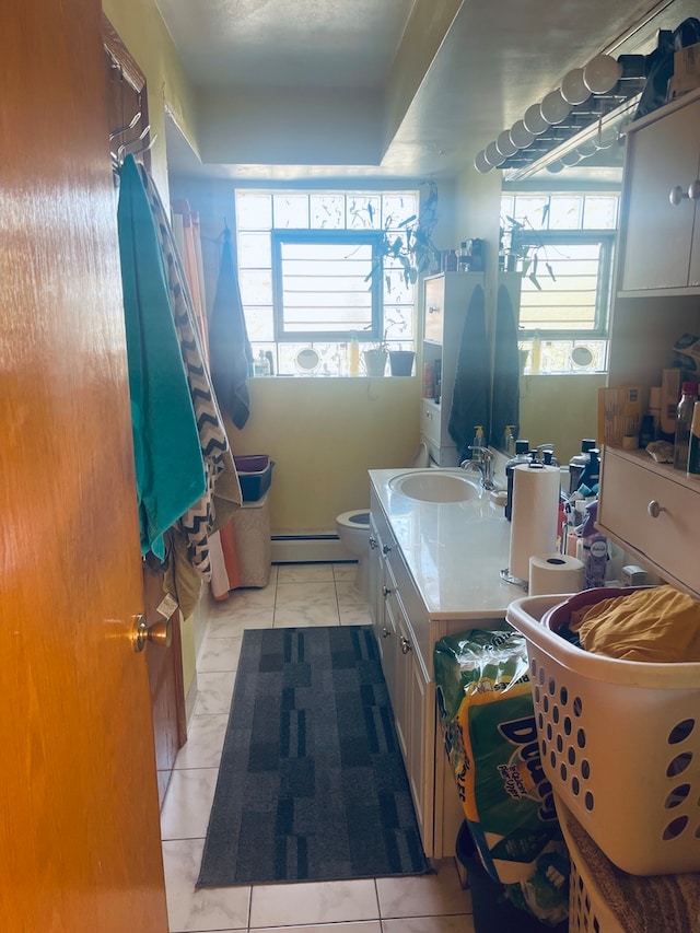 bathroom with vanity, toilet, a baseboard heating unit, and plenty of natural light