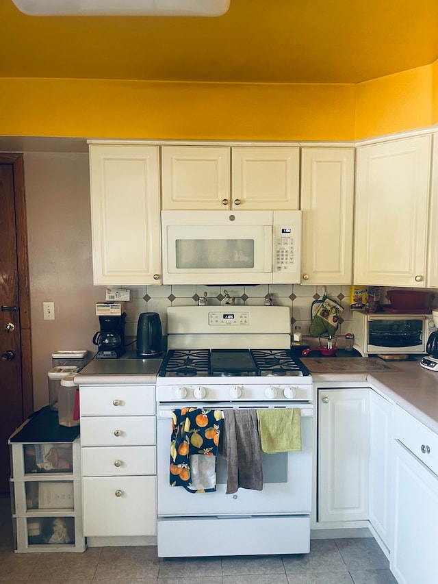 kitchen featuring white cabinets, tasteful backsplash, light tile patterned floors, and white appliances