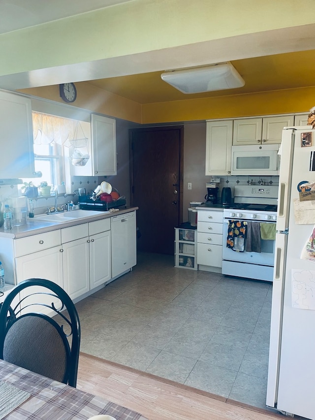 kitchen with sink, light wood-type flooring, white cabinets, white appliances, and tasteful backsplash