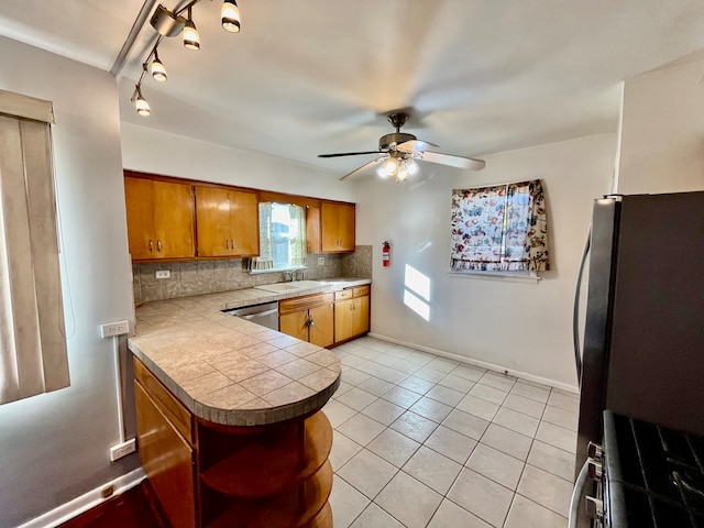 kitchen with kitchen peninsula, decorative backsplash, ceiling fan, light tile patterned flooring, and stainless steel appliances