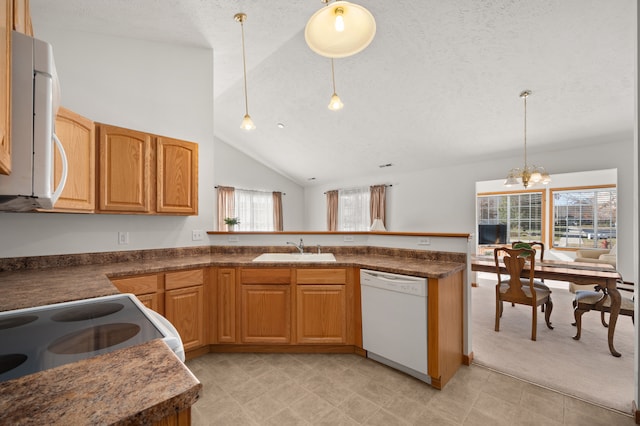 kitchen with sink, hanging light fixtures, white appliances, and kitchen peninsula