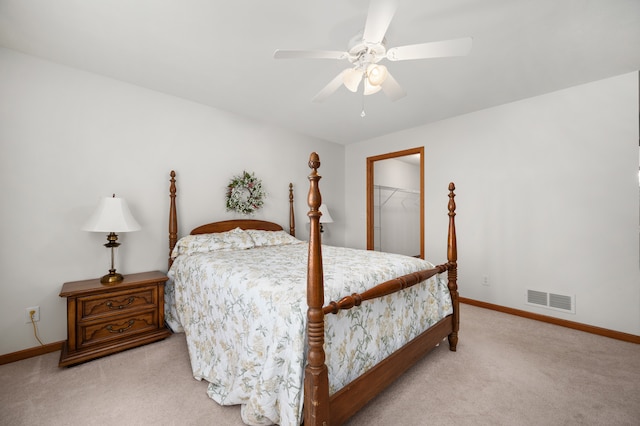 bedroom with light carpet, a closet, ceiling fan, and a walk in closet