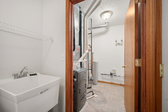 clothes washing area featuring light colored carpet, a textured ceiling, and sink