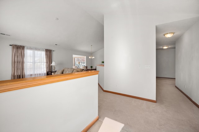 interior space featuring a notable chandelier, lofted ceiling, and light colored carpet