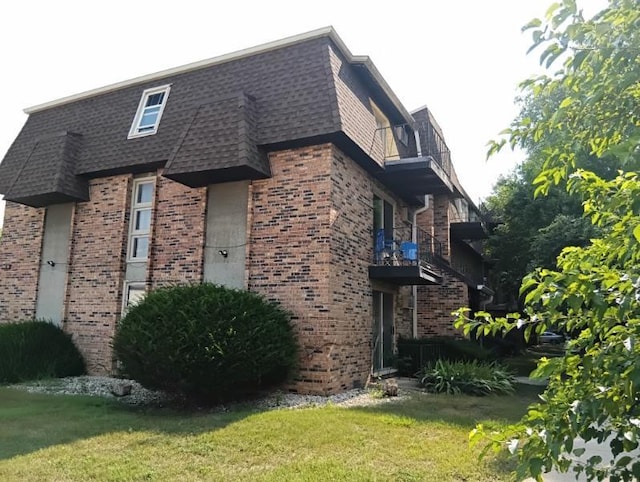 view of side of property with a lawn and a balcony