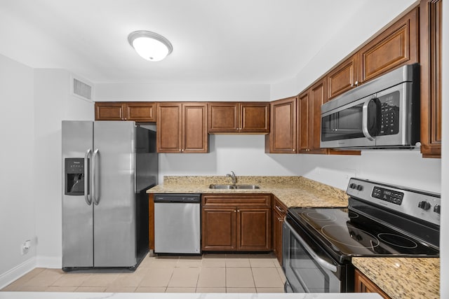 kitchen with sink, light tile patterned flooring, light stone counters, and stainless steel appliances