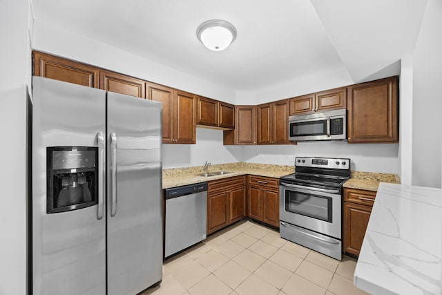 kitchen with sink, light stone countertops, stainless steel appliances, and light tile patterned floors