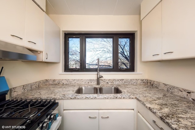 kitchen with light stone countertops, white cabinetry, sink, and range with gas cooktop