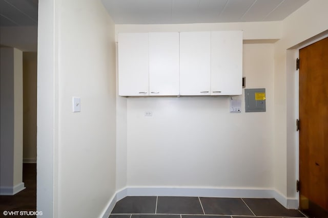 clothes washing area featuring dark tile patterned flooring and electric panel