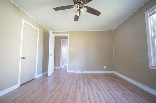 interior space with ornamental molding, light wood-type flooring, and ceiling fan