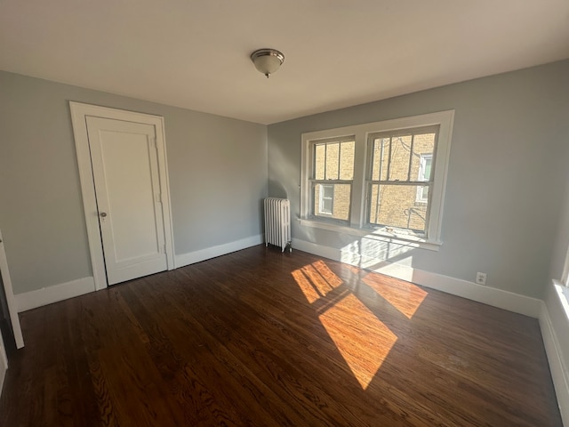 spare room with radiator heating unit and dark hardwood / wood-style flooring