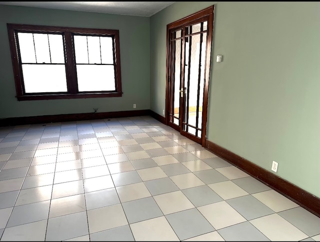 empty room with a healthy amount of sunlight and light tile patterned floors