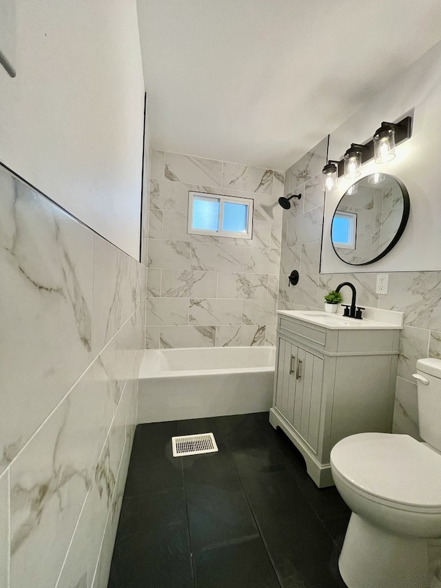 full bathroom with vanity, tile walls, tiled shower / bath combo, and toilet