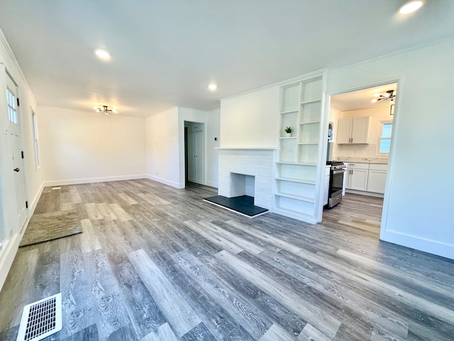 unfurnished living room with light hardwood / wood-style floors, a fireplace, and built in shelves