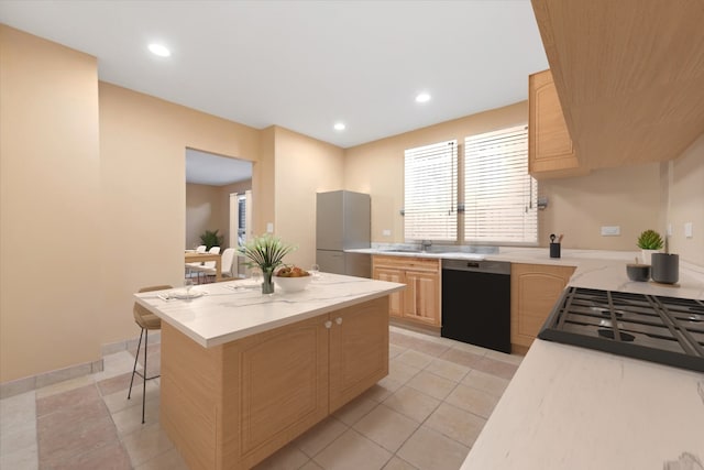 kitchen featuring light brown cabinetry, sink, dishwasher, a kitchen breakfast bar, and light tile patterned floors