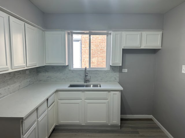 kitchen with dark wood-type flooring, tasteful backsplash, white cabinetry, and sink