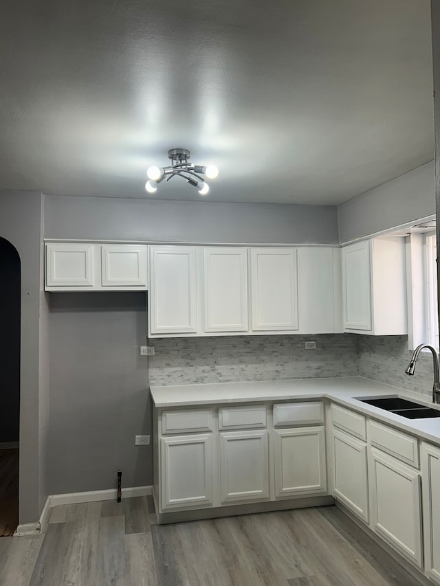 kitchen featuring light hardwood / wood-style floors, white cabinets, sink, ceiling fan, and backsplash