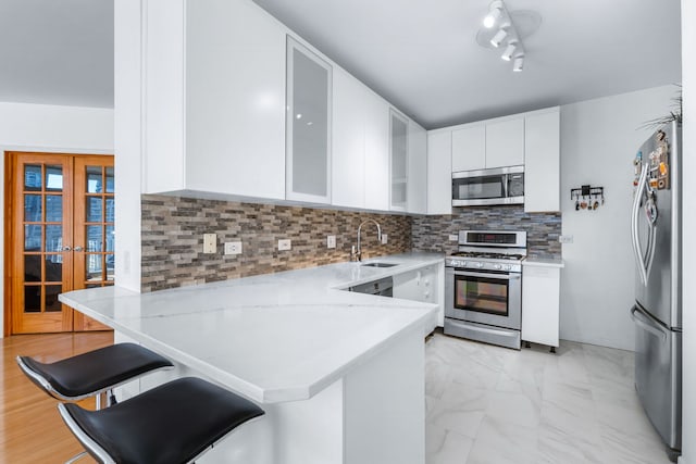 kitchen with kitchen peninsula, white cabinets, a breakfast bar, french doors, and stainless steel appliances