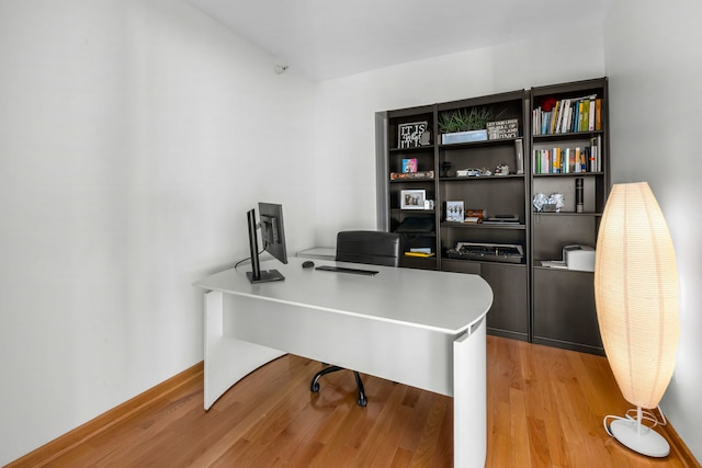 home office with light hardwood / wood-style flooring