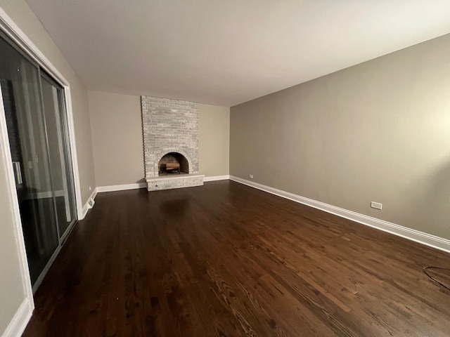 unfurnished living room featuring dark hardwood / wood-style flooring and a brick fireplace