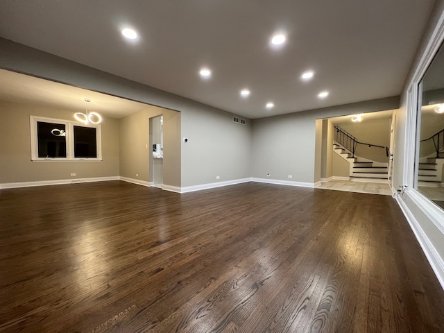 unfurnished living room featuring an inviting chandelier and dark hardwood / wood-style floors