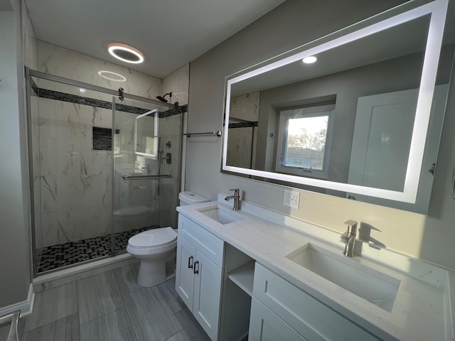 bathroom featuring vanity, toilet, and a shower with shower door