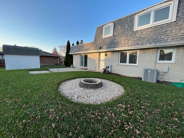 rear view of property with an outdoor fire pit, a lawn, and central AC unit