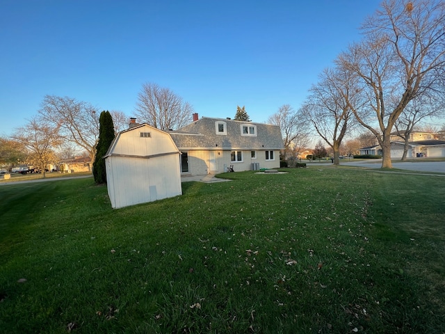 rear view of property with a shed and a lawn