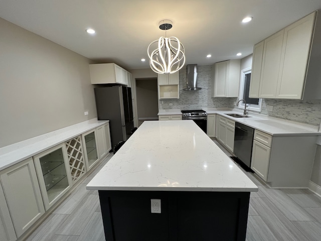 kitchen with hanging light fixtures, appliances with stainless steel finishes, light stone countertops, wall chimney exhaust hood, and a center island