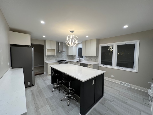 kitchen with wall chimney exhaust hood, sink, a center island, pendant lighting, and appliances with stainless steel finishes