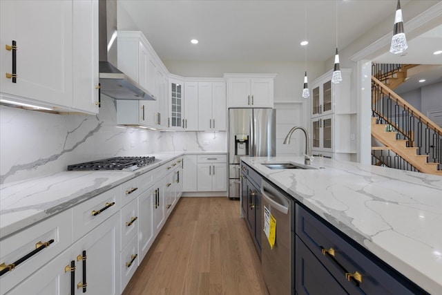 kitchen featuring white cabinetry, wall chimney exhaust hood, sink, and appliances with stainless steel finishes