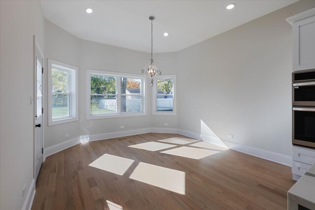 unfurnished dining area featuring a chandelier and light wood-type flooring